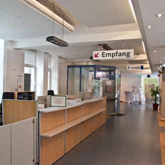 Empfangsbereich Jobcenter Zossen, ein langer Tresen, darüber Schild mit Aufschrift Empfang.