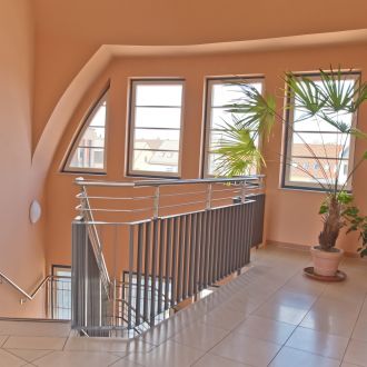 Treppenhaus des Jobcenters, glänzende Fliesen, Lachsfarbenen Wänden, Edelstahl Geländer.